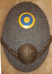 Mössmärke m/39 (m/14-39) grå mössoval i plåt 55x80) Typ 3 (1942 och framåt) med nationalitetsmärke m/41, gradbeteckning galon i form av beläggningssnöre i bronsfärg, fastsydd i vinkel samt knapp m/1865 i brons 22 mm till pälsmössa m/04 och m/09