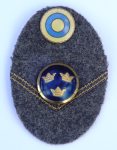 Mössmärke m/46, mössoval i vadmal 50x75 mm med nationalitesmärke m/41, gradbeteckning galon i bronsfärg, fastsydd i vinkel bestående av dubbla beläggningssnören samt knapp m/1865 till uniform m/39 fält- och vintermössa m/43